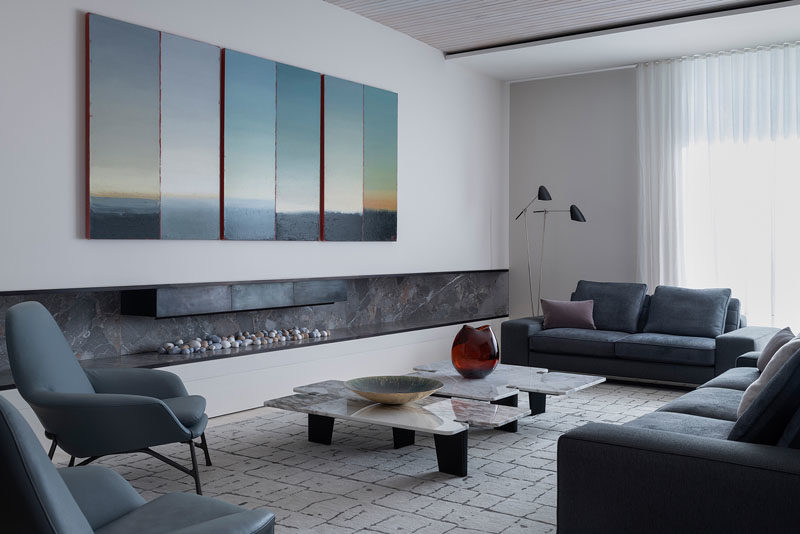 Living Room Ideas - In this modern living room, the six panels of Philip Wolfhagen’s landscape ‘Third Proposition: Triptych’ stretches over an extra wide fireplace mantle. #LivingRoom #Fireplace #LivingRoomIdeas