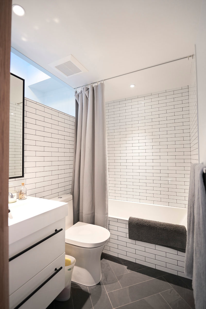 Bathroom Design Ideas - In this modern bathroom, white subway tiles line the walls, while a shower curtain hangs from a track in the ceiling. #BathroomIdeas #BathroomDesignIdeas #ShowerCurtain