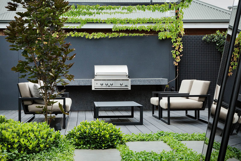 Landscaping Ideas - This modern outdoor lounge also has a dedicated BBQ area along the fence, with ivy growing above it. #LandscapingIdeas #OutdoorLounge #BBQ