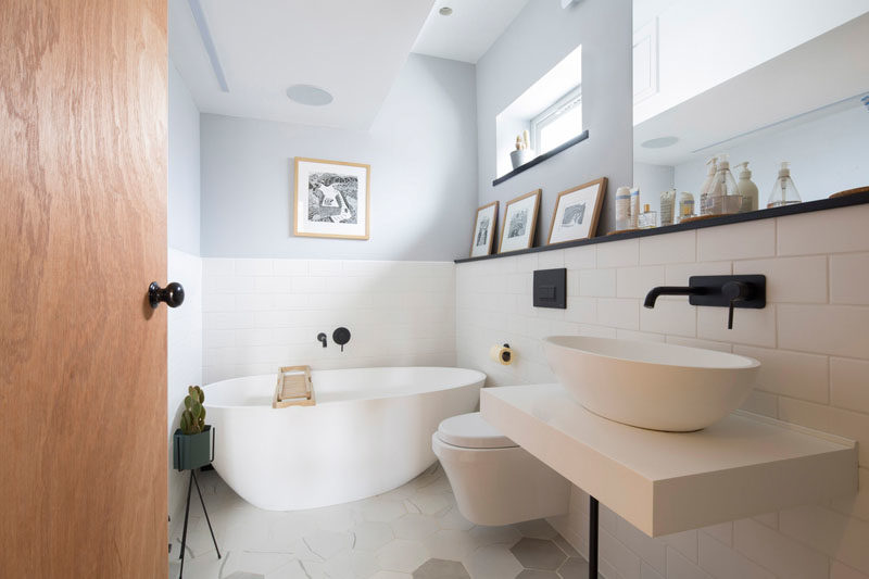 Bathroom Ideas - In this modern bathroom, the lower half of the room has been kept white, while a picture rail provides a place to display art and also acts as a small space for storing items above the vanity. #BathroomIdeas #ModernBathroom #BathroomDesign