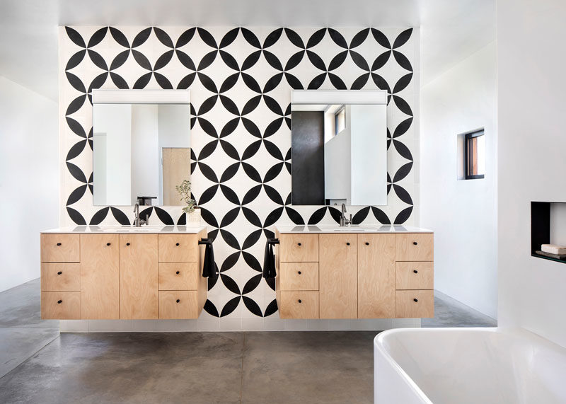 Bathroom Ideas - In this modern ensuite bathroom, black and white patterned tiles create a bold statement, and provide a backdrop for the floating wood vanities. #BathroomIdeas #BathroomDesign #PatternedTiles #FloatingVanity