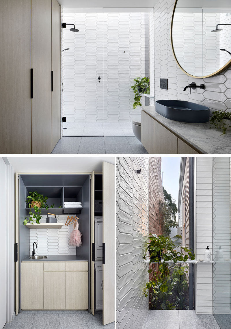 Bathroom Ideas - In this modern white bathroom,  white picket tiles cover the walls, while the laundry is hidden away in wood cabinets opposite the vanity, and in the shower, there's a floor-to-ceiling window with views of a tiny garden at the side of the house. #BathroomIdeas #PicketTiles #WhiteTiles #HiddenLaundry #Windows