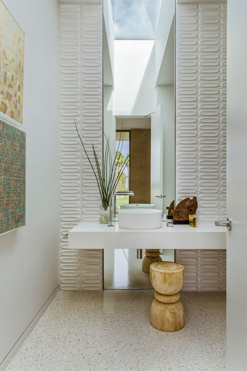 This modern bathroom features a tall mirror that reflects the light from the skylight, while tiles on either side add a textural element to the room. #ModernBathroom #Skylight #BathroomDesignIdeas