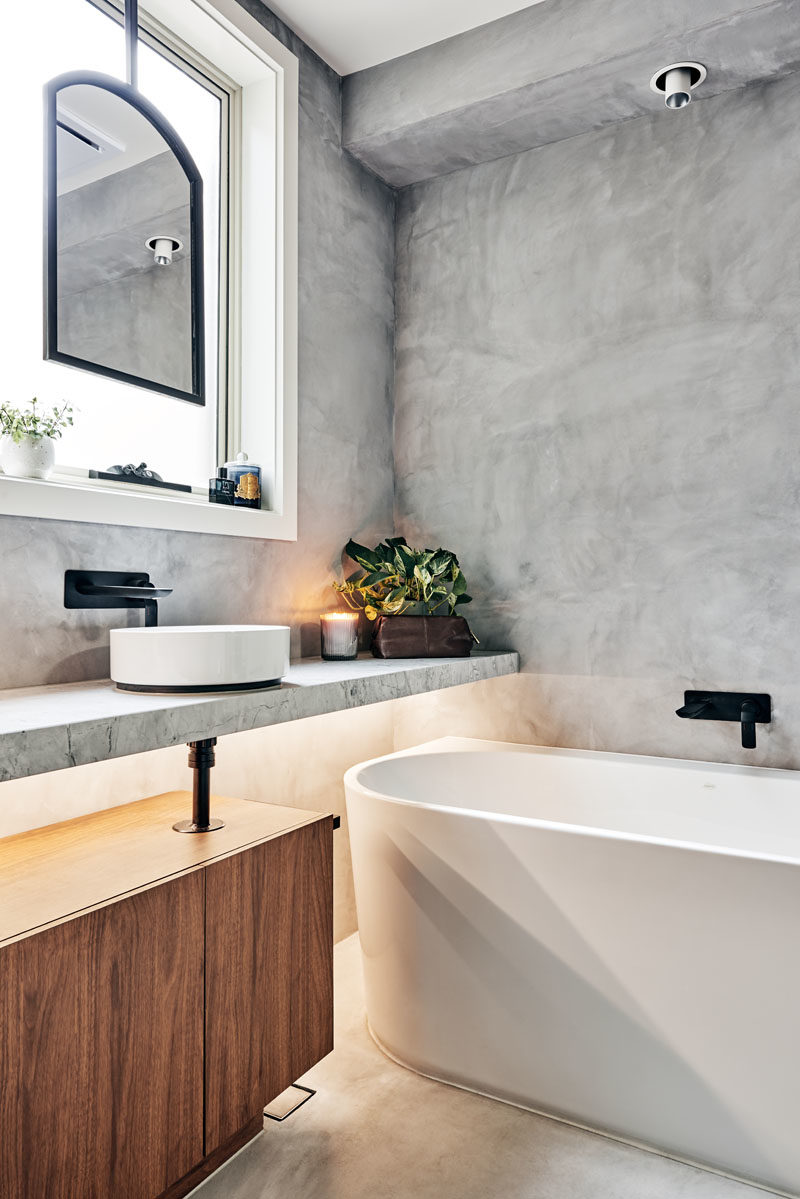 Bathroom Ideas - A matte black metal framed custom mirror suspended in front of a window, allowed the designers to maintain natural light and ventilation, while the white bathtub slightly tucked under a floating vanity bench, helped to o achieve the ultimate desired luxury of a soaking bath. #BathroomIdeas #ModernBathroom