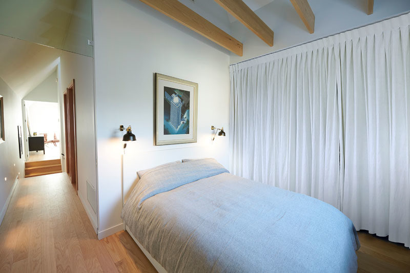 In this modern guest bedroom, furnishings have been kept minimal and a curtain lines the wall, while wood beams have been left exposed. #BedroomDesign #BedroomIdeas