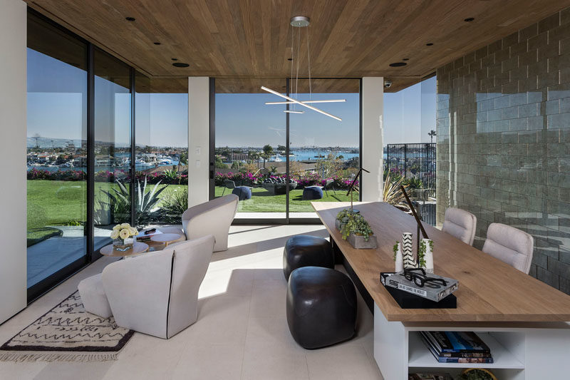 Home Office Ideas - This modern bright home office, features a floor-to-ceiling sliding doors, a tiled wall, and a wood ceiling. #HomeOffice #GlassWalls #WoodCeiling