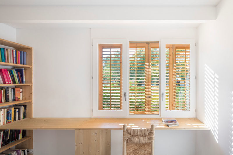 Home Office Ideas - This home office has a single wood desk that can be used by two people, and is connected to a wood bookshelf. #HomeOffice #Desk #WoodDeskIdeas