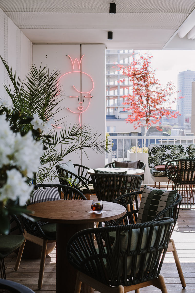 Rooftop Deck Ideas - This modern rooftop cocktail bar has an almost tropical appearance, with leaf-print upholstery, wood flooring, and plants. #TropicalDesign #RooftopDeck #OutdoorSpace