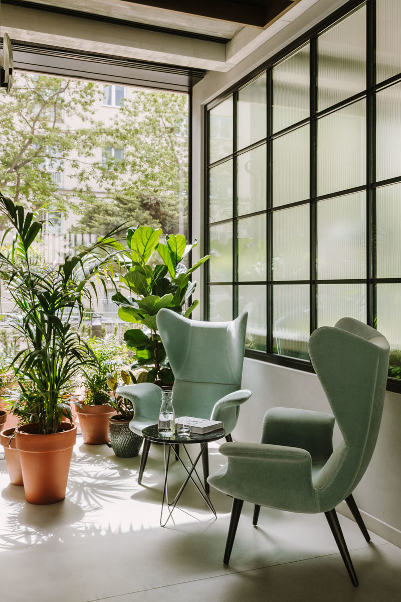 Decor Ideas - Green armchairs and potted plants sit beside a black-framed wall of windows, creating an almost tropical appearance. #DecorIdeas #Seating #Plants #Windows