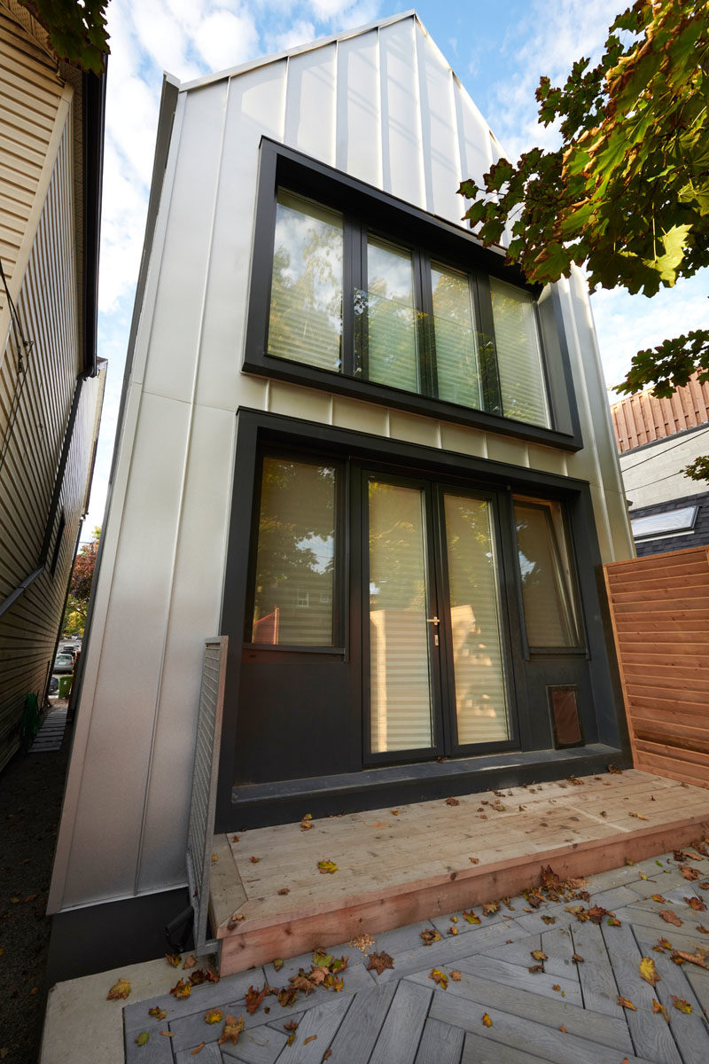 Doors off the living room open up the rear of this modern house to the yard, that provides a view of the black-framed windows on the second floor. #BlackWindowFrames #Architecture #ModernHouse