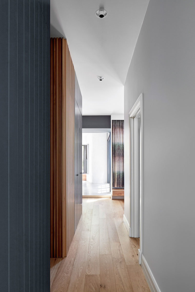 Một hành lang kết nối các không gian sinh hoạt khác nhau ở phía sau ngôi nhà với phòng làm việc, hai phòng ngủ và phòng tắm.  #ModernInterior #ModernHallway # WoodFloors