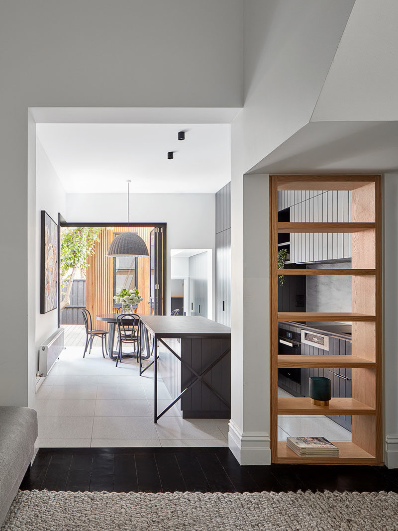 Shelving Ideas - From the front hallway of this renovated house, you're able to see the kitchen through an open bookshelf that's been built into the wall. #Bookshelf #ShelvingIdeas #WoodShelf #OpenShelf