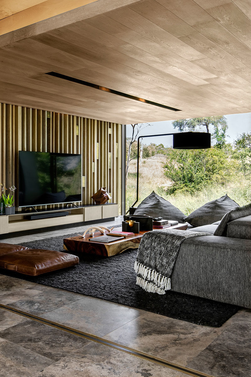 Living Room Ideas - This modern living room has a wood ceiling, a wood slat accent wall, and grey furnishings, which when combined, create a modern but relaxed look. #LivingRoomIdeas #WoodCeiling #WoodAccentWall