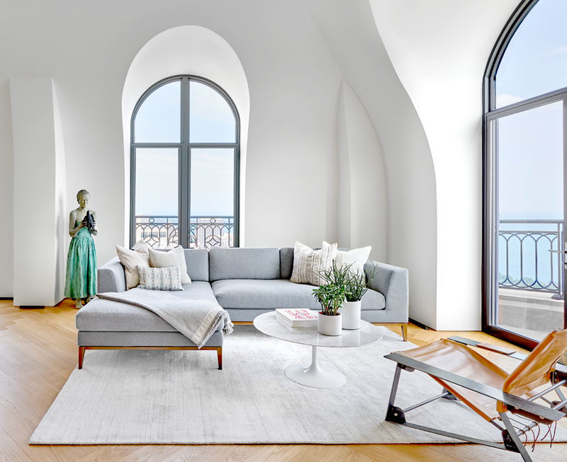 Living Room Ideas - This modern living room features minimal furnishings in soft colors, to create a relaxing and calm atmosphere. Arched windows and vaulted ceilings help to keep the space bright and open. #LivingRoomIdeas #ModernInterior #LivingRoom