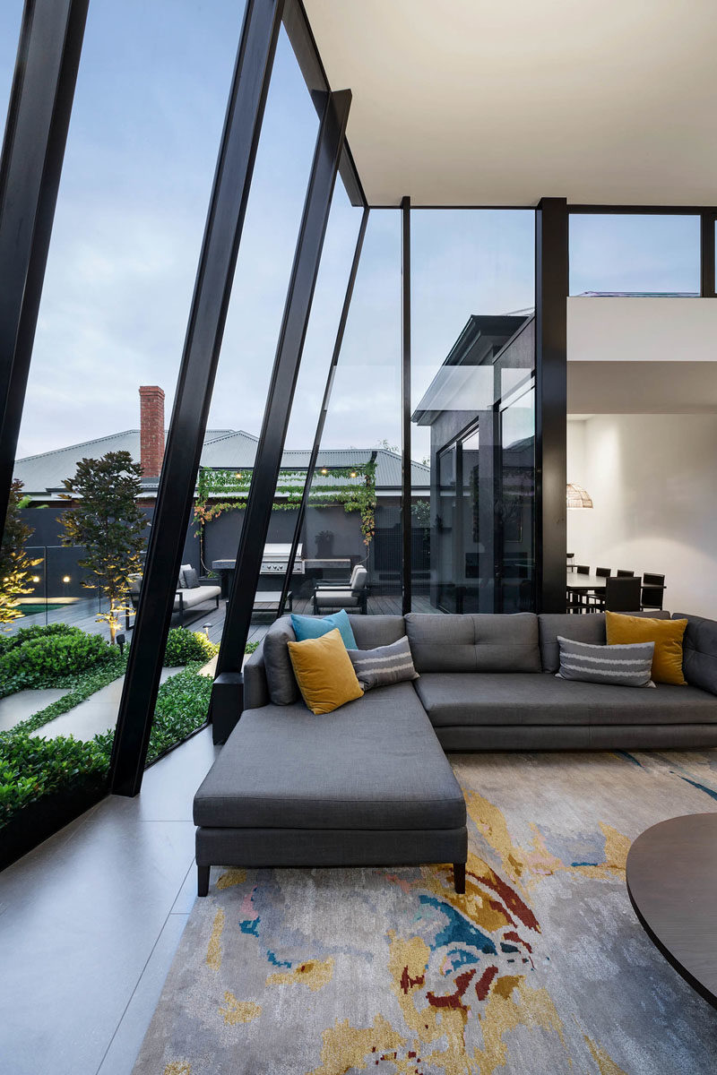 Window Ideas - At the end of the hallway in this modern house, there's an open plan living room, dining room, and kitchen, with soaring ceiling heights and floor-to-ceiling windows, that introduce a sense of space, light and scale to the residence. #ModernInterior #WindowIdeas #WindowDesign #LivingRoom #LivingRoomIdeas