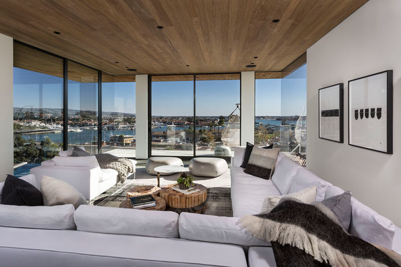 Living Room Ideas - This modern and mostly white living room has glass walls to take advantage of the surrounding views. #LivingRoom #WhiteLivingRoom #GlassWalls #WoodCeiling