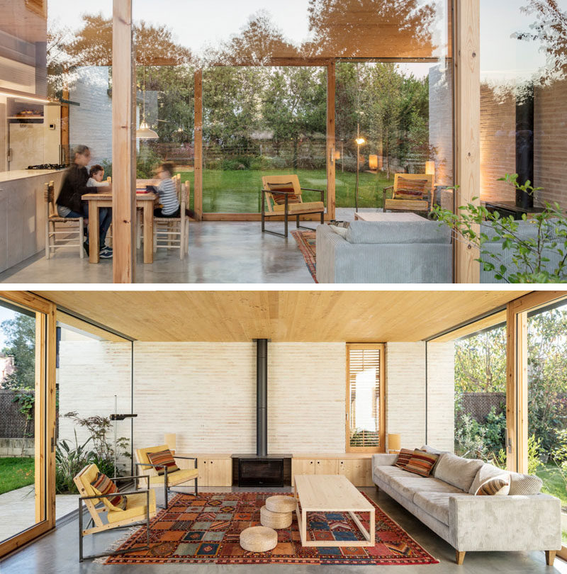 This modern house has an open floor plan with the living room enjoying a fireplace with built-in storage on either side. #The two glass walls have sliding doors that open to the garden. #LivingRoom #Fireplace #GlassWalls