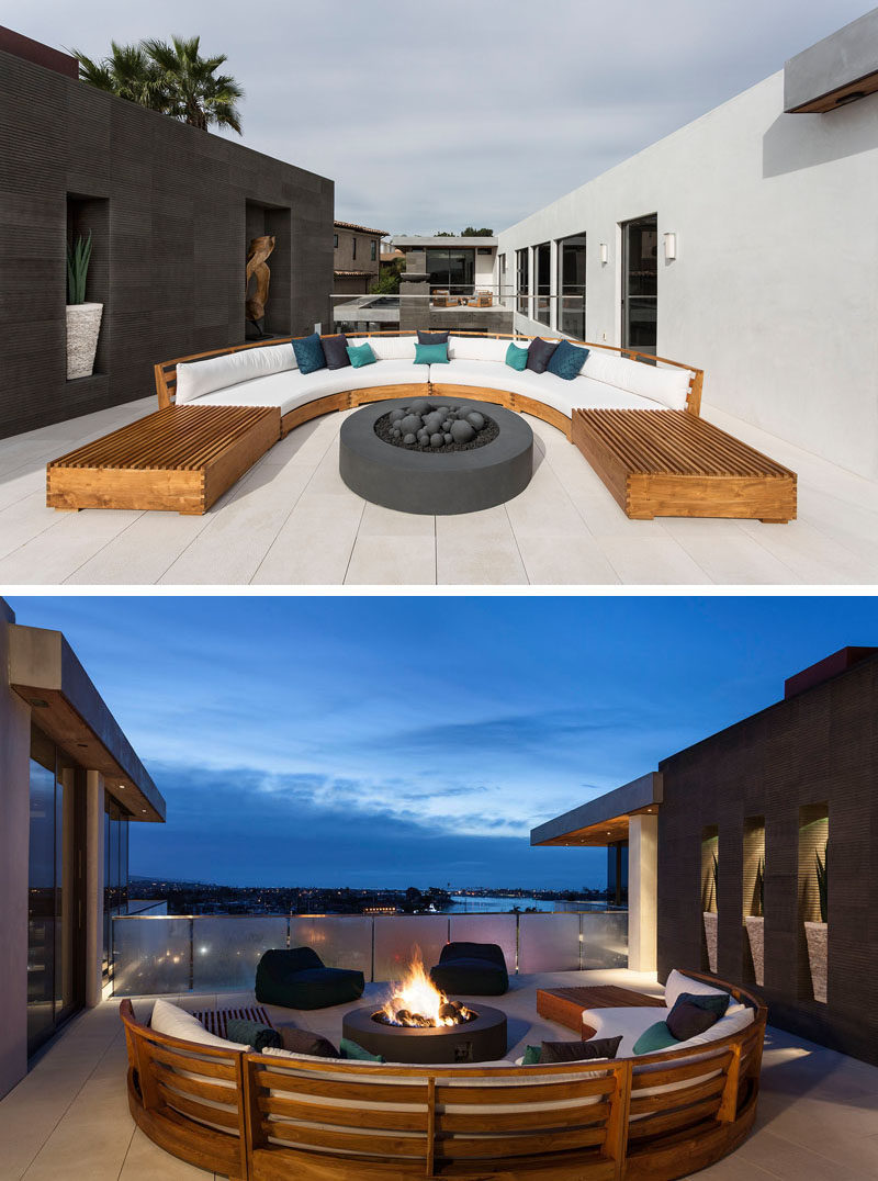 This outdoor entertaining area has a curved wood couch with white upholstered cushions, and a freestanding firepit. #OutdoorLounge #CurvedOutdoorFurniture #Firepit