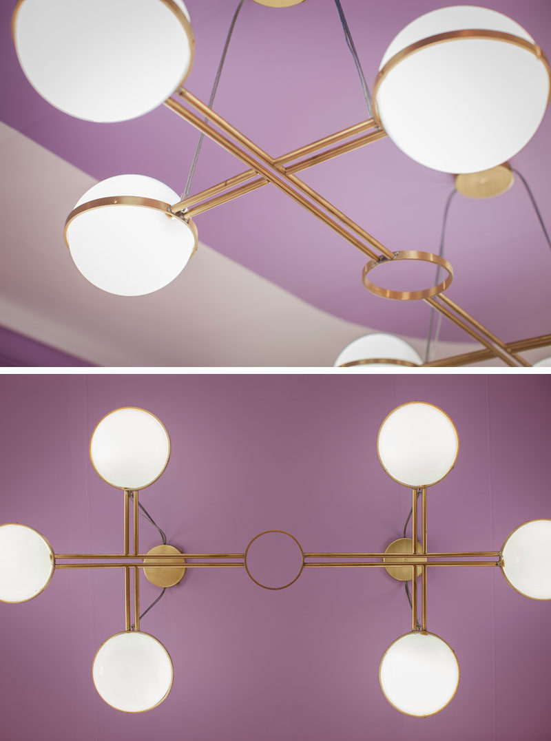 Bold lighting with a brass frame draws the eye upwards in this mostly purple hotel suite. #Lighting #LightingDesign