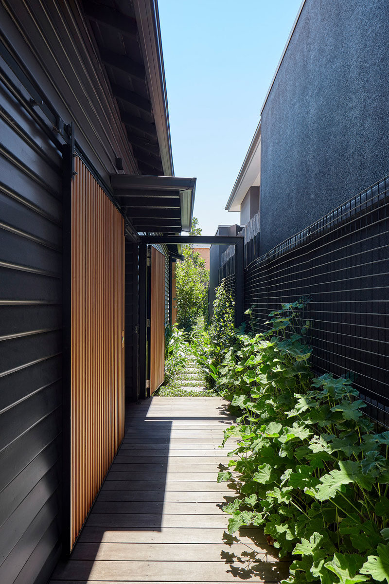 A ramp that runs down the side of this modern house, leads to the front door, and a stepping stone path continues to the backyard. #Ramp #Landscaping #BlackSiding