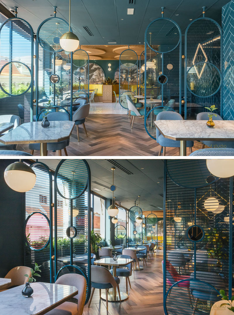 This modern restaurant features room dividers made from blue painted metal with circular cut-outs. The curved ends create a softer appearance, while the horizontal lines allow light to travel through them. #RoomDivider #RestaurantDesign #InteriorDesign #Screen