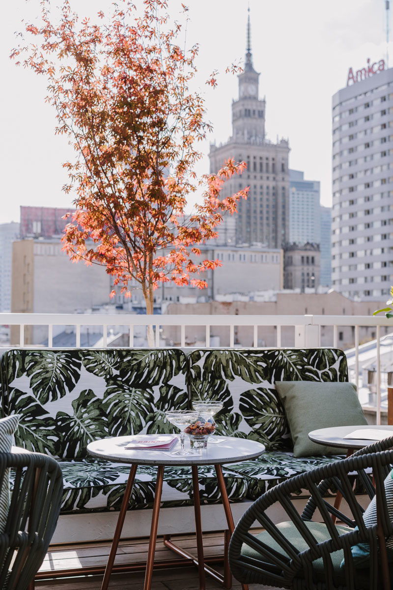 Rooftop Deck Ideas - This modern rooftop cocktail bar has an almost tropical appearance, with leaf-print upholstery, wood flooring, and plants. #TropicalDesign #RooftopDeck #OutdoorSpace