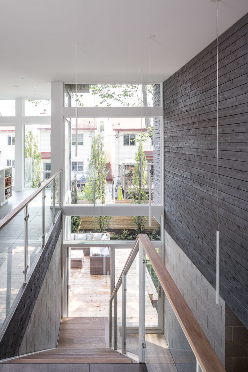 Stair Ideas - This modern open-riser stair rises up through a large double-height space, while honed concrete-block walls and grey-stained cedar siding are showcased on the walls. #StairIdeas #Stairs #Staircase #ModernStairs #CedarSiding #WoodAccentWall