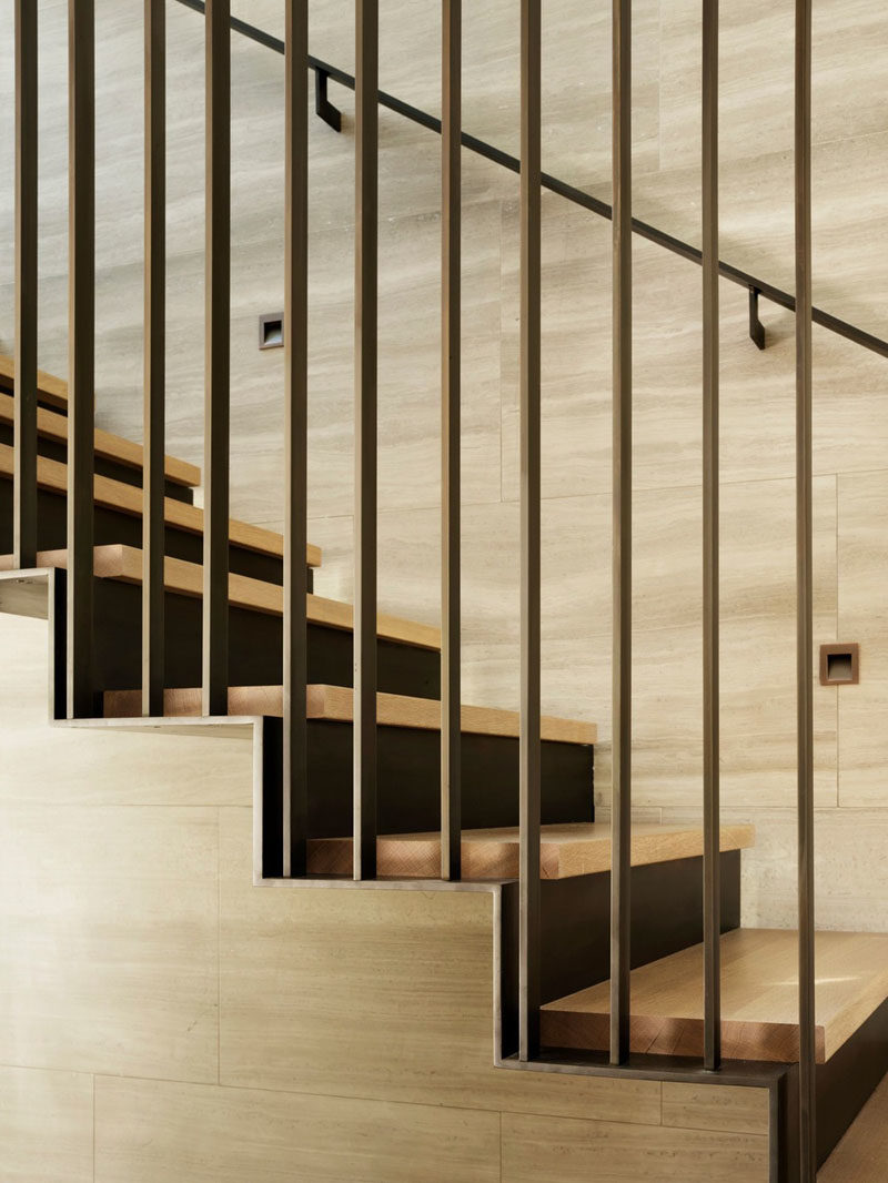 A three-story staircase connects the various levels of this modern house, and showcases a muted material palette, consisting of soft tan Haisa marble, European white oak, and blackened steel. #ModernStairs #Staircase #SteelStairs