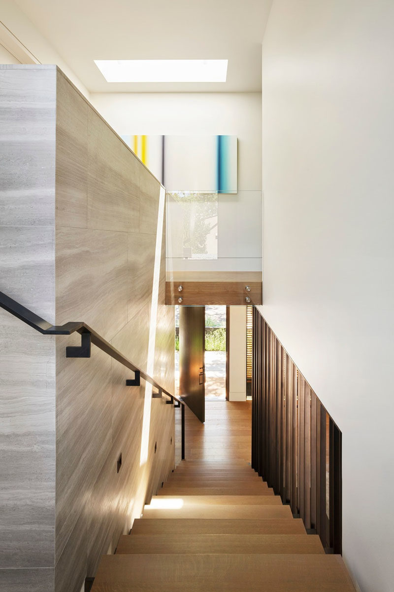 A three-story staircase connects the various levels of this modern house, and showcases a muted material palette, consisting of soft tan Haisa marble, European white oak, and blackened steel. #ModernStairs #Staircase #SteelStairs