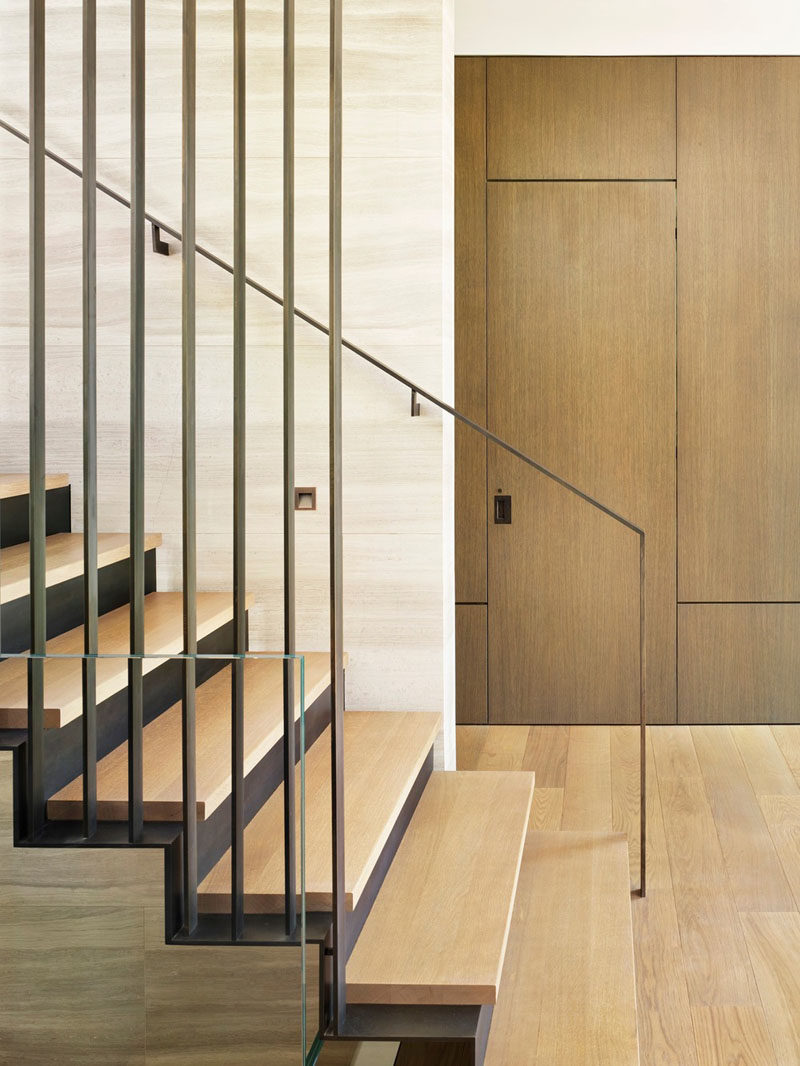 A three-story staircase connects the various levels of this modern house, and showcases a muted material palette, consisting of soft tan Haisa marble, European white oak, and blackened steel. #ModernStairs #Staircase #SteelStairs