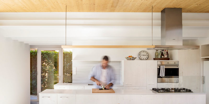 The wood ceiling in this modern house adds a natural touch to the all white kitchen. #KitchenDesign #WhiteKitchen