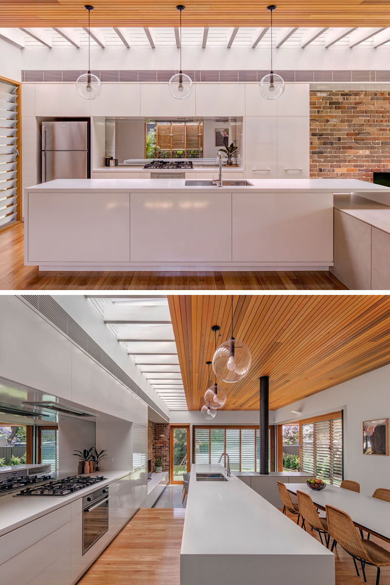 Kitchen Ideas - In this modern all-white kitchen, there's a skylight to add natural light, and a mirrored backsplash that reflects the herb garden outside. #KitchenIdeas #KitchenDesign #WhiteKitchen #KitchenSkylight #MirroredBacksplash