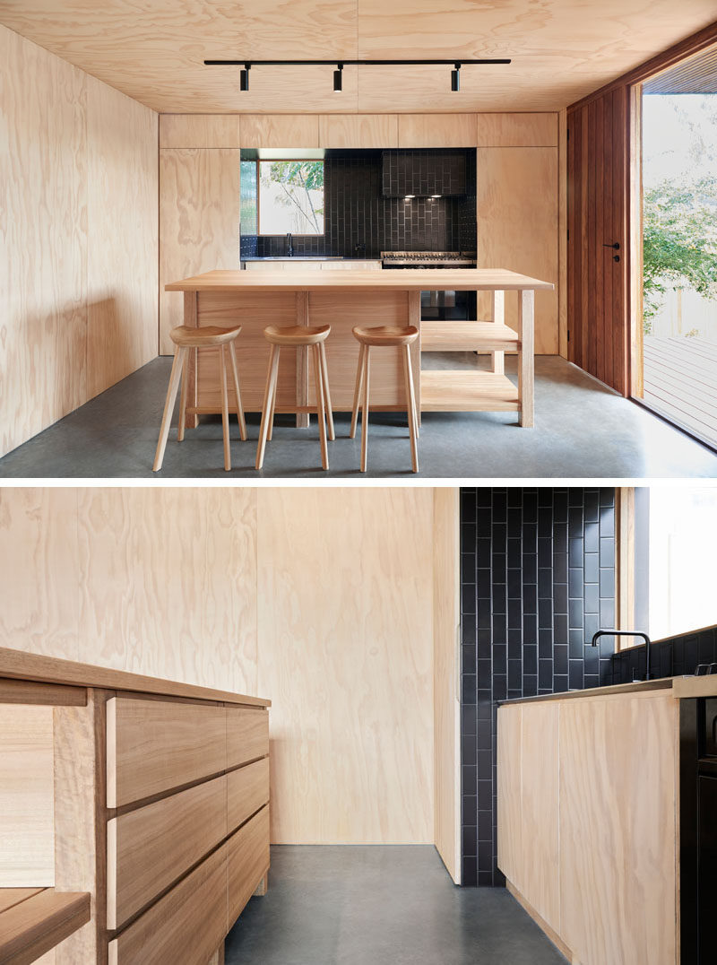 Polished concrete floors are featured throughout this small modern house, while black vertical subway tile and track lighting in the kitchen a strong contrast to the light plywood walls. #BlackTiles #KitchenDesign #PlywoodKitchen #PlywoodInterior