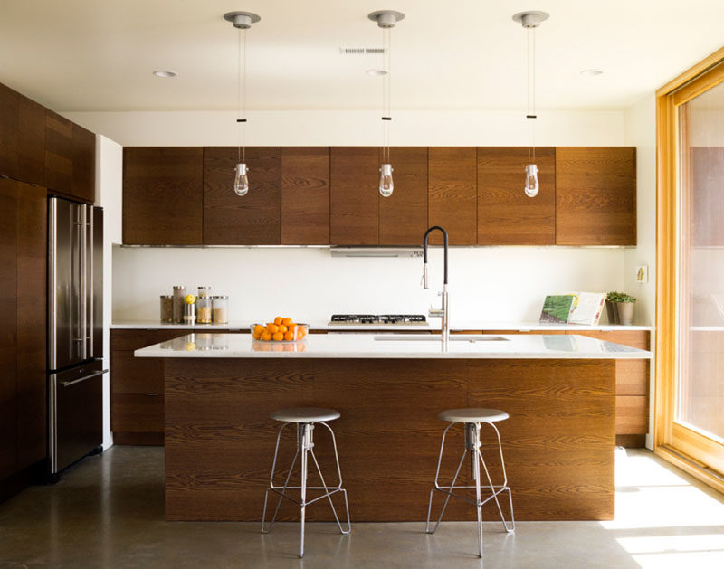 Kitchen Ideas - This modern kitchen with an island, has warm wood cabinets with white countertops and backsplash. #KitchenIdeas #KitchenDesign #WoodKitchen #ModernKitchen