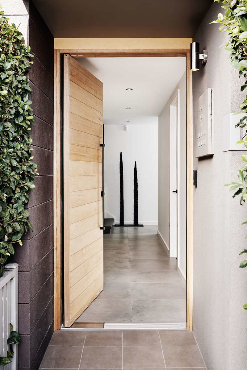 Door Ideas - This modern townhouse has a light wood front door that features a large modern black vertical handle. #ModernDoor, #DoorDesign #DoorIdeas #WoodDoor