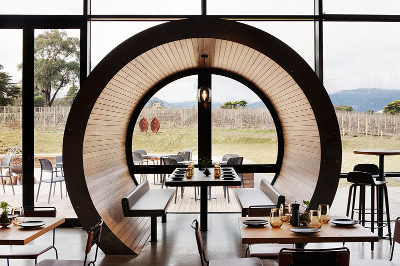 Restaurant Design Ideas - Timber lined barrel booths are positioned along one of the walls of windows in this restaurant, creating a semi-private dining experience, and referencing the wine barrels used within the winery. #RestaurantIdeas #RestaurantDesign #Winery #Seating #Booths