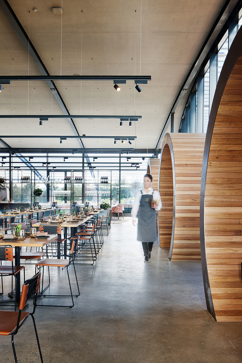 Restaurant Design Ideas - Timber lined barrel booths are positioned along one of the walls of windows in this restaurant, creating a semi-private dining experience, and referencing the wine barrels used within the winery. #RestaurantIdeas #RestaurantDesign #Winery #Seating #Booths