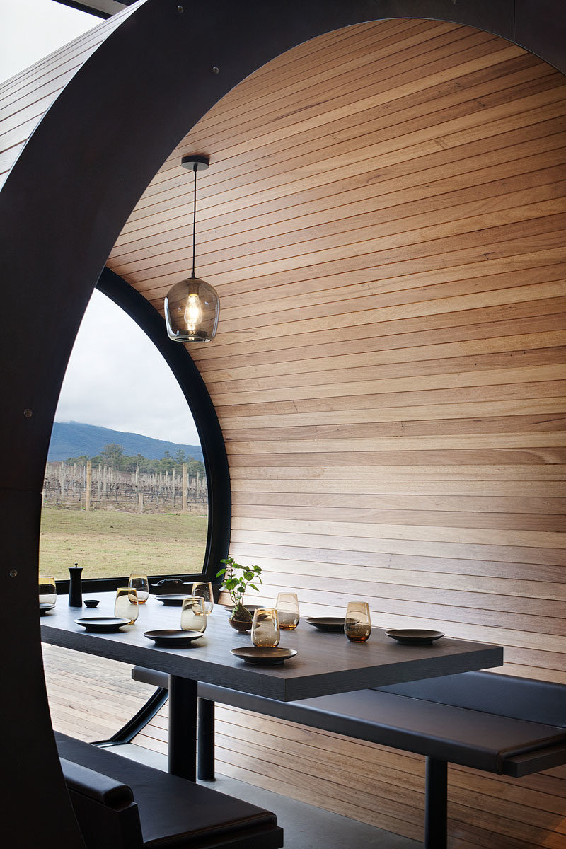 Restaurant Design Ideas - Timber lined barrel booths are positioned along one of the walls of windows in this restaurant, creating a semi-private dining experience, and referencing the wine barrels used within the winery. #RestaurantIdeas #RestaurantDesign #Winery #Seating #Booths