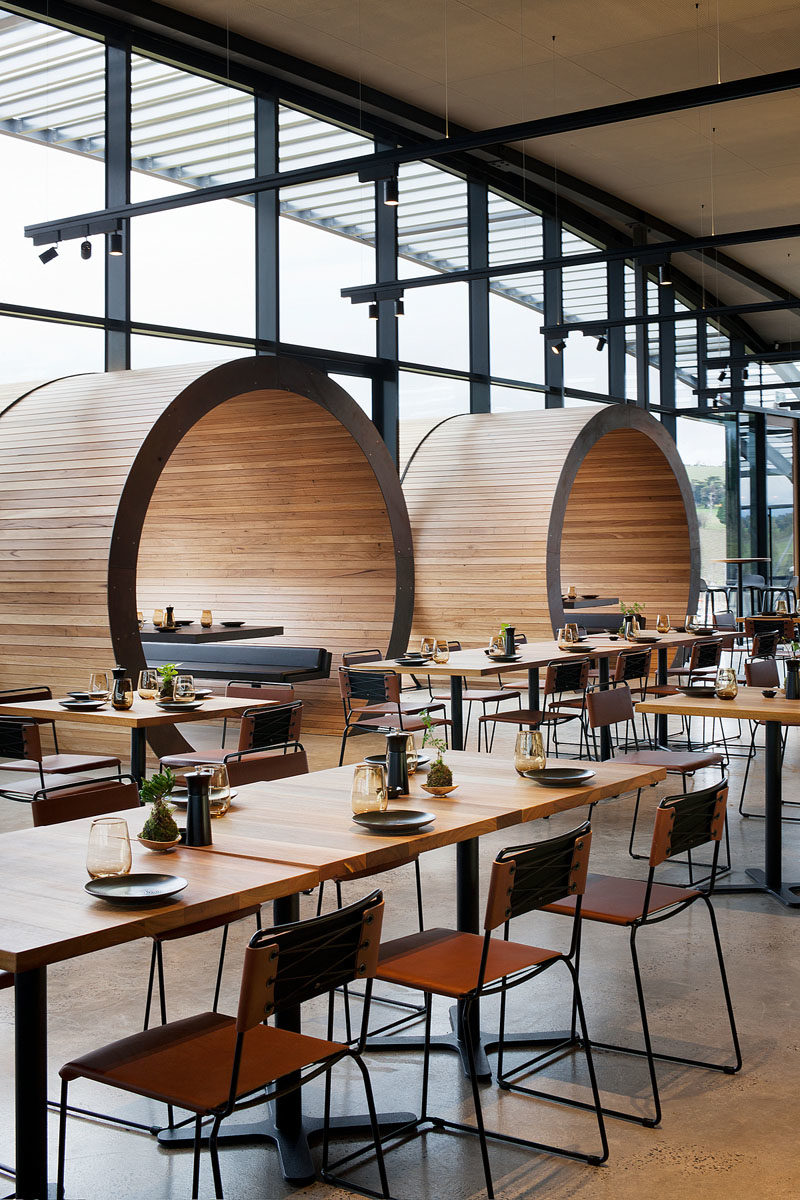 Restaurant Design Ideas - Timber lined barrel booths are positioned along one of the walls of windows in this restaurant, creating a semi-private dining experience, and referencing the wine barrels used within the winery. #RestaurantIdeas #RestaurantDesign #Winery #Seating #Booths