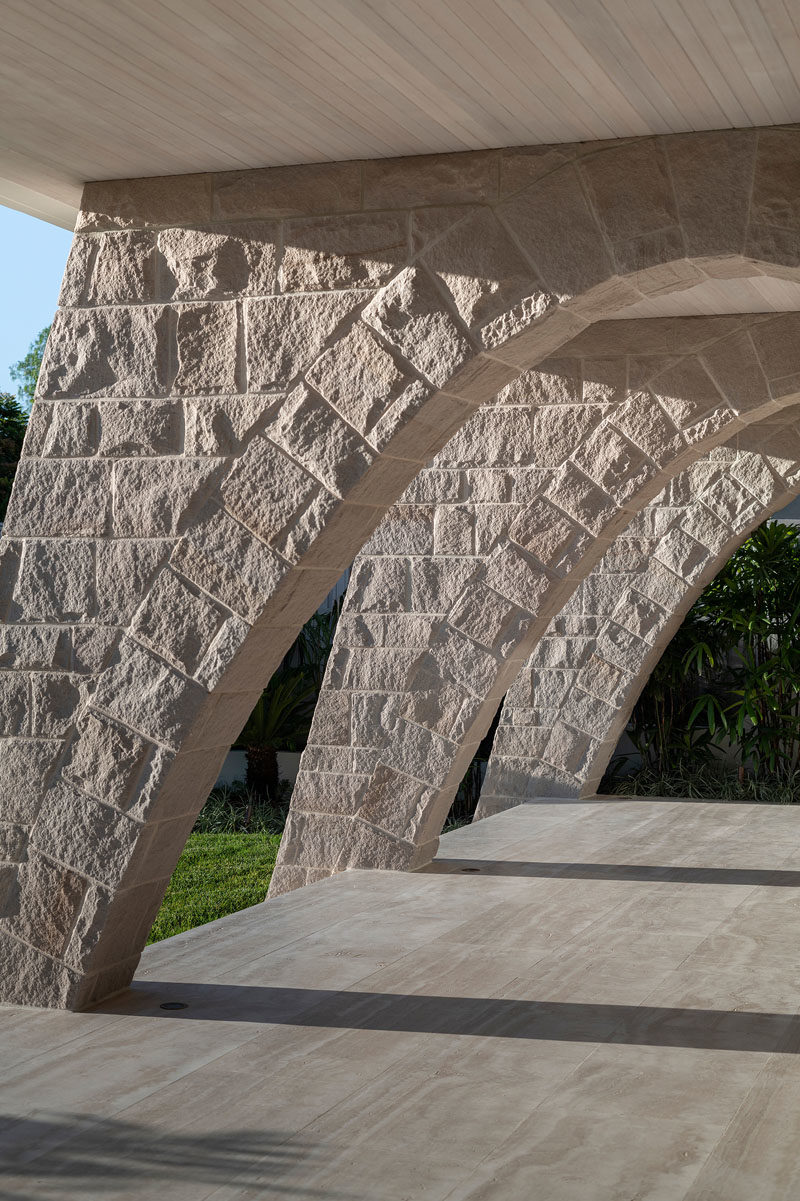 On the ground floor of this modern house, sandstone arches, lined timber ceiling boards, and travertine flooring form a powerful, tough, and muscular base to the home. #SandstoneArches #ModernHouse #ModernArchitecture #TravertineFlooring