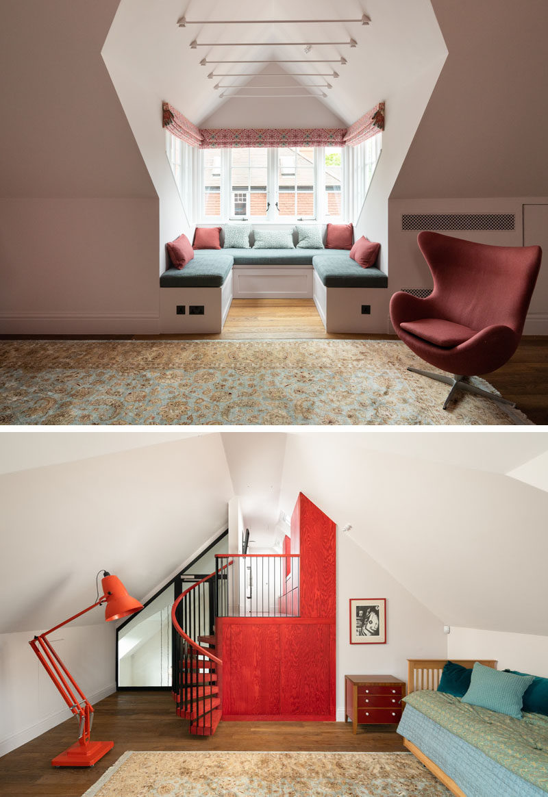 A recessed window bench seat has been added to this open room offering a peaceful spot for reading and reflection. On the opposite wall is a bright red accent wall with a spiral staircase. #WindowSeat #WindowBench #InteriorDesign #SpiralStairs