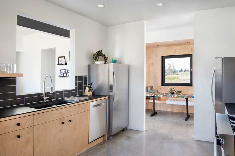 Kitchen Ideas - In this modern kitchen, black tile matches the black countertops, while the wood cabinets complement the wood used on for the casual breakfast nook. #KitchenIdeas #BlackTile #KitchenDesign