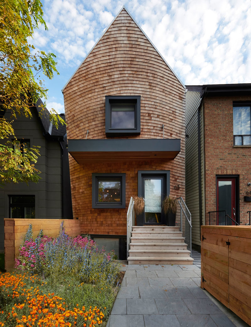 House Design Ideas - This curved house combines wood shingles and black accents for a modern appearance. #Shingles #ModernHouse #BlackWindowFrames #HouseDesignIdeas