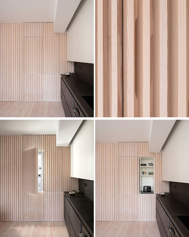 Interior Design Ideas - The wood slat wall in this modern apartment incorporates secret doors, and all storage and service requirements for the apartment, including kitchen appliances and hanging cupboards, resulting in a highly efficient plan. #InteriorDesignIdeas #WoodSlatWall #HiddenAppliances #HiddenFridge #IntegratedFridge #HiddenStorage #SecretDoors #HiddenDoors