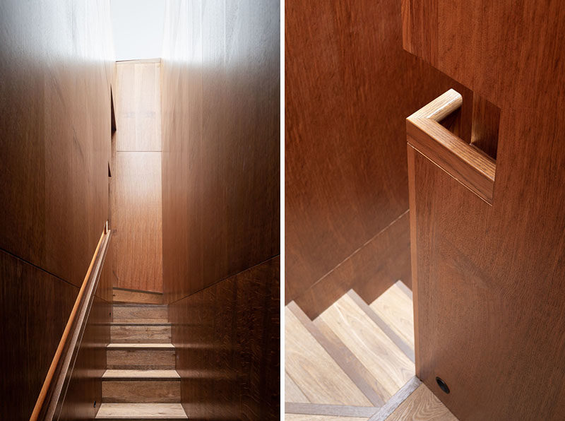 Staircase Ideas - This modern staircase clad in Brown Oak wraps itself up behind the library, forming a distinctive space, lit by the full length skylight above. Recessed LED lighting guides the occupants up to the second story of the library, and highlights the careful craftsmanship of the integrated handrail. #StairIdeas #HandrailIdeas #Staircase #Handrail #BuiltInHandrail