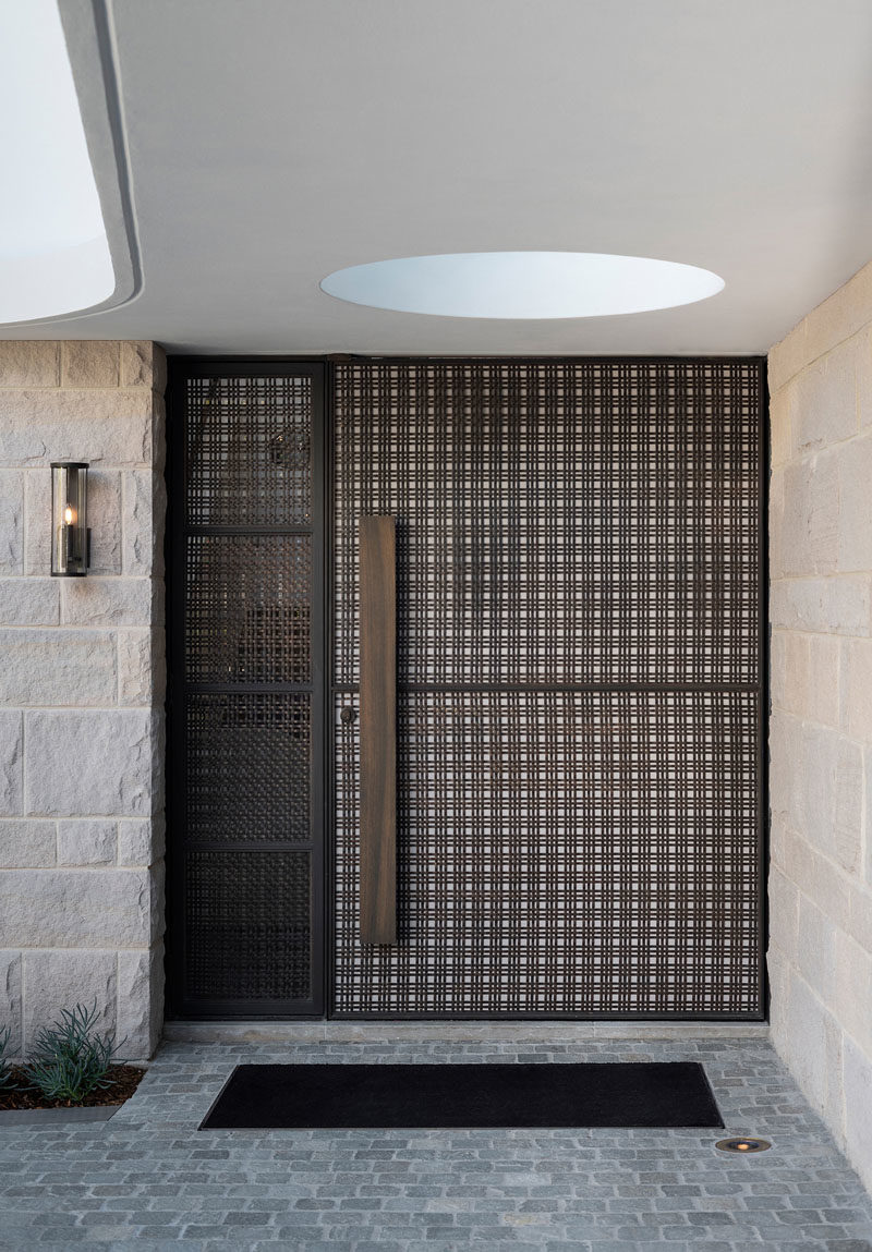 Front Door Ideas - This modern front door has a brass woven ribbon mesh exterior, and a travertine slab interior. #ModernFrontDoor #DoorIdeas #FrontDoor