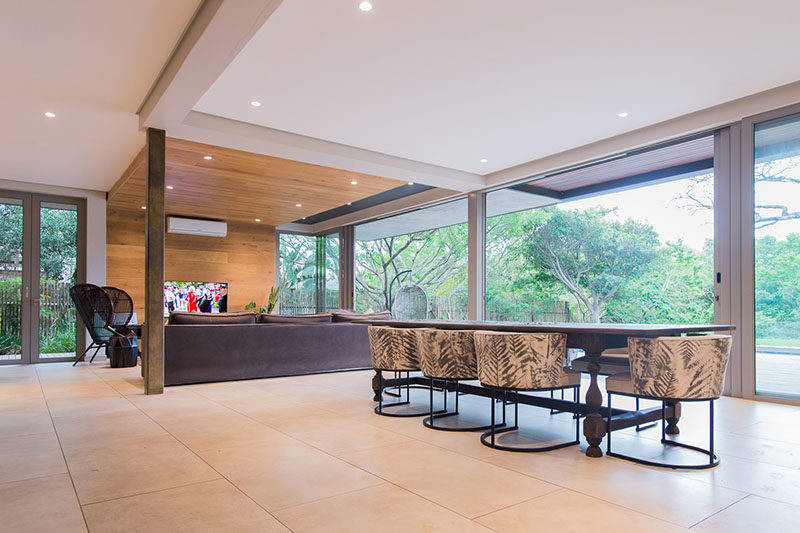 LIVING ROOM IDEAS - One of the most eye-catching design elements of this modern interior by Metropole Architects, was the inclusion of a wrap-around wood accent wall in the living room that travels from the wall up onto the ceiling. #LivingRoom #WoodAccentWall #WoodCeiling #InteriorDesign #AccentWall #LivingRoomIdeas