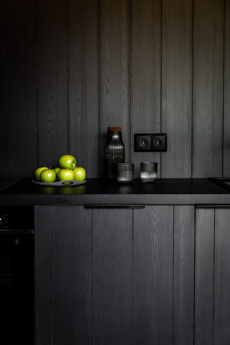 Kitchen Ideas - In this modern black kitchen, black cabinets complement the black dining furniture, the black structural elements, and the black window frames. #BlackKitchen #KitchenIdeas #ModernKitchen #KitchenDesign