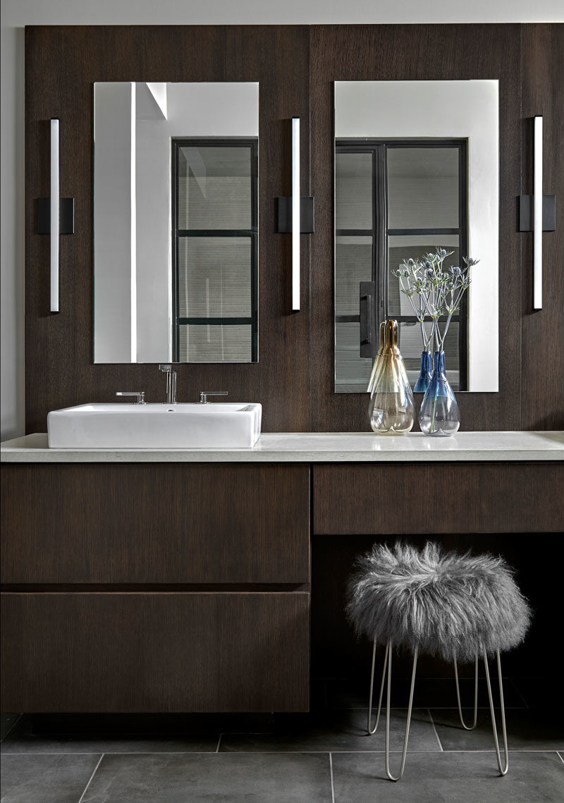 Bathroom Ideas - This modern bathroom features a wall hung  vanity and back panel that's made from rift cut white oak with an espresso stain. Matching back panel. An engineered quartz counter is complemented by Kohler Compose faucets with a titanium finish, while gray porcelain tiles cover the floor. #BathroomIdeas #ModernBathroom #DarkWoodVanity #MasterBathroom