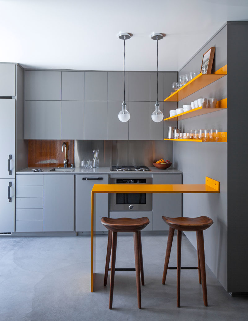 Kitchen Ideas - Stepping inside this modern micro apartment, and the kitchen cabinetry, countertops, and concrete floor exactly match in color, achieved with an integral additive color for the concrete. #GreyAndYellow #SmallKitchen #KitchenDesign #KitchenIdeas